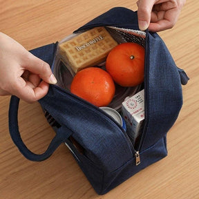 Bolsa térmica portátil carregando frutas, biscoito, lata de refrigerante, caixinha de suco e uma marmita de almoço